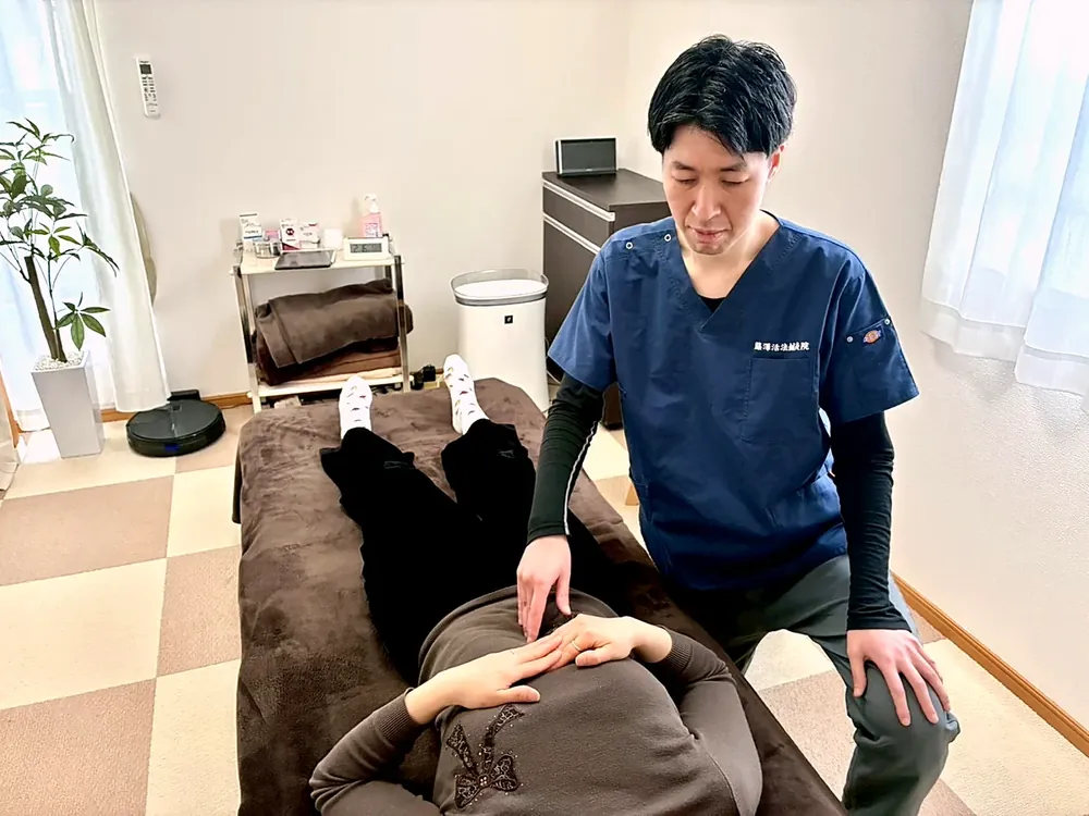 仰向けの状態で、お腹まわりに手を当てている様子