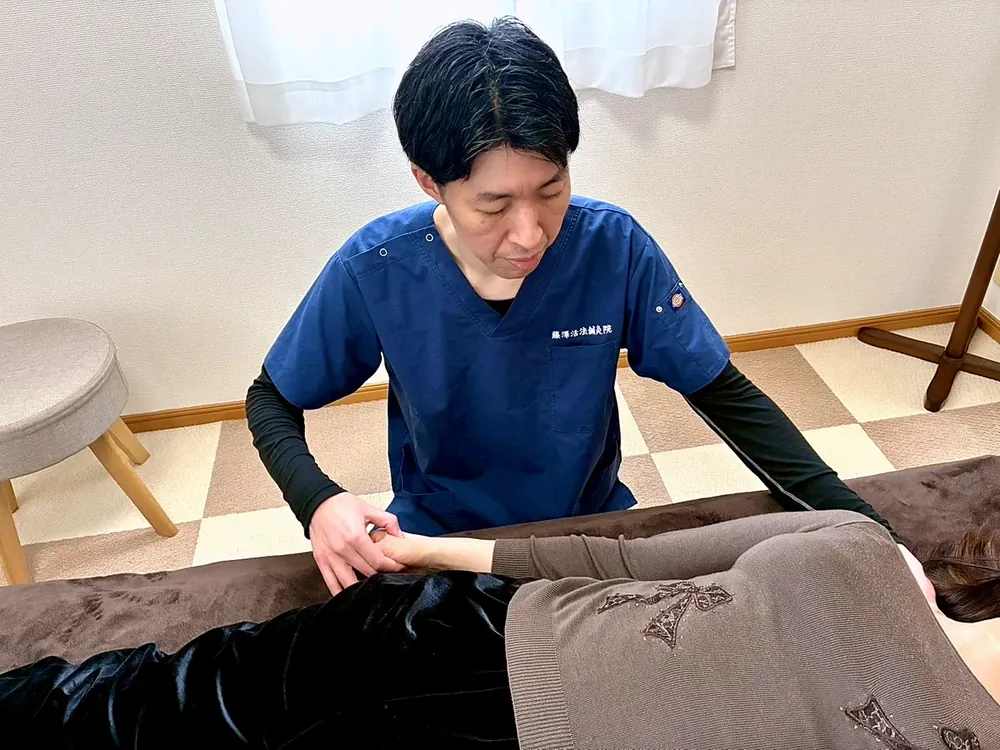 手首にそっと触れて施術している様子
