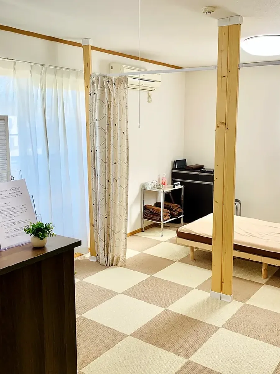 院内の様子。手前に受付カウンター、仕切りカーテンの奥に施術ベッドがある