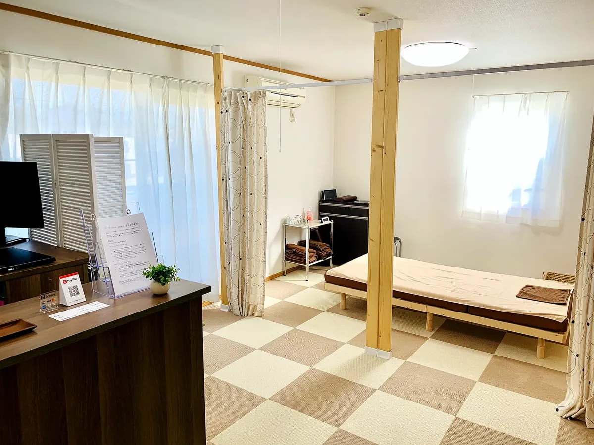 明るい自然光が入る院内。施術ベッドと受付カウンター